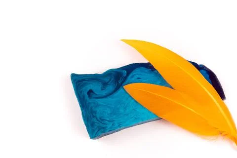 Thin flat piece of blue mint handmade soap and two orange feathers Stock Photos