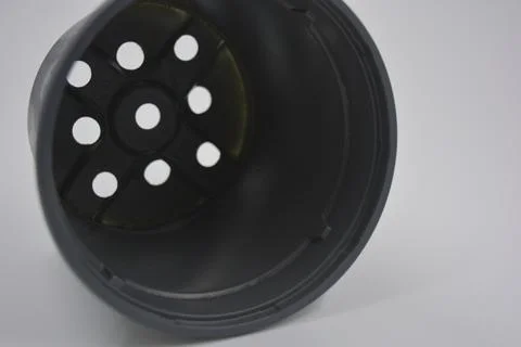 Thin gray plastic flower pot, the container is arranged on a white plastic. Stock Photos