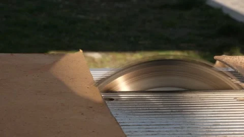 Thin hardboard sheet approaches spinning circular saw blade and begins to be cut Stock Footage 332875830
