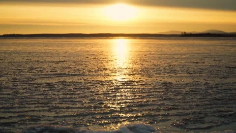 Thin ice on the water surface of the lake in the rays of the setting sun. Stock Footage 286130179