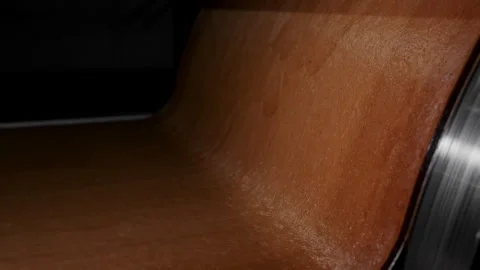 A thin layer of dark caramel falls from the drum onto a conveyor belt. Stock Footage 295132996