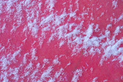 Thin layer of snow on a red synthetic woven surface, background Stock Photos