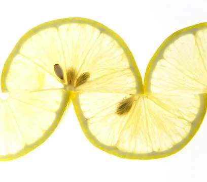 Thin lemon slices are folded in a pattern on a white background. Stock Photos