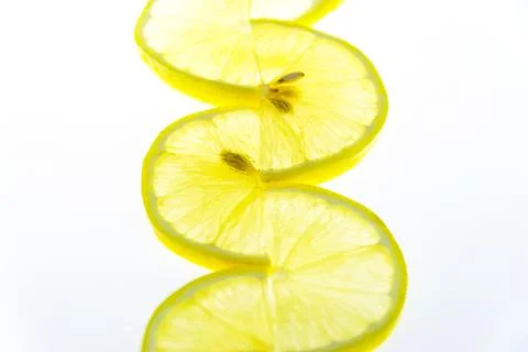 Thin lemon slices are folded in a pattern on a white background. Stock Photos