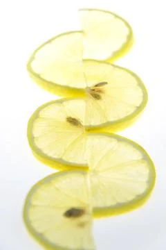 Thin lemon slices are folded in a pattern on a white background. Foto stock