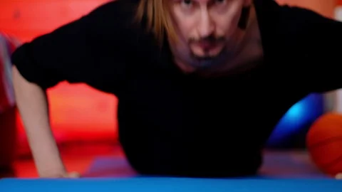 A thin long-haired man in dark clothes is pushing himself from the floor of the 動画素材 128649777