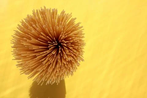 Thin long spaghetti on a yellow background. Raw italian pasta from above Stock Photos