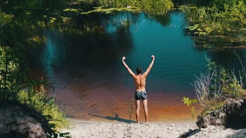 Thin man doing exercises on the shore of wild river Stock Footage