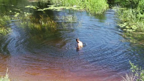 Thin man swims in the wild river summer day Stock Footage