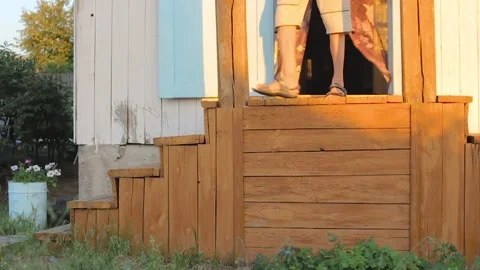 Thin man walks down stairs, porch of country house, open door of cabin in suburb 스톡 동영상 170848110