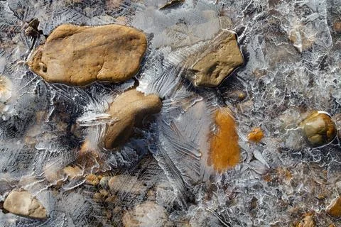 Thin openwork ice covered the river stones Stock Photos
