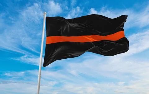 Thin Orange Line flag waving at sky background on sunset, panoramic view. cop Illustrazione stock