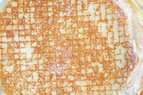 A thin pancake background. Cooking thin pancakes with holes in the pan. Fried Stock Photos
