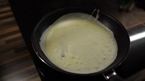 Thin pancake is baked in a frying pan with steam Stock Footage 282093241