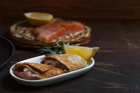 Thin pancake roll with weak salt salmon and cream cheese close-up, on a dark  Stock Photos