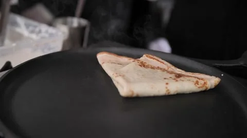 Thin pancakes are cooked in a frying pan on an open fire in the open air. Stock-Footage 229556535