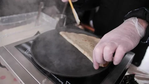 Thin pancakes are cooked in a frying pan on an open fire in the open air. Stock Footage 229556543