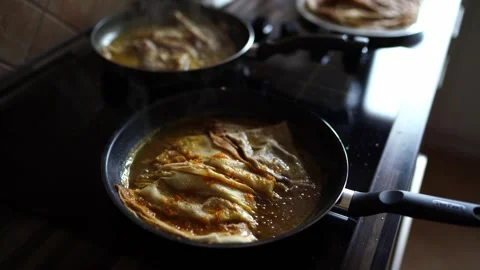 Thin pancakes boil in orange sauce in pans Stock Footage 280674936