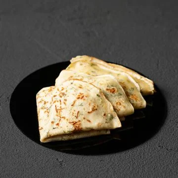 Thin pancakes with dill on gray background. Simple crepes with herbs or greens Stock Photos