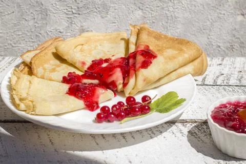 Thin pancakes with red currant jam on a light background. Traditional Russian Stock Photos