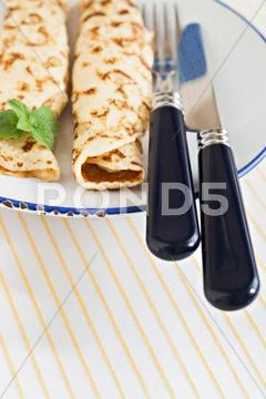 Thin pancakes rolled crepes mint on a plate with knife and fork Stock Photos