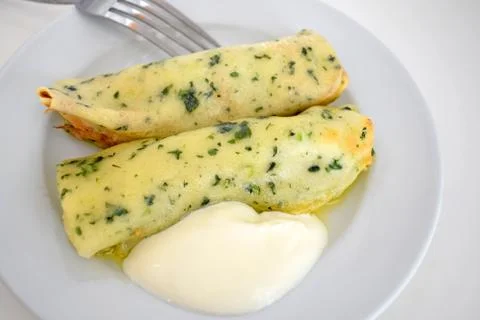 Thin pancakes stuffed with spinach and sour cream on a white plate. Low-calor Stock Photos
