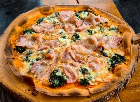 Thin Pizza with vegeteble and becon toping serving on wooden plate. Stock Photos