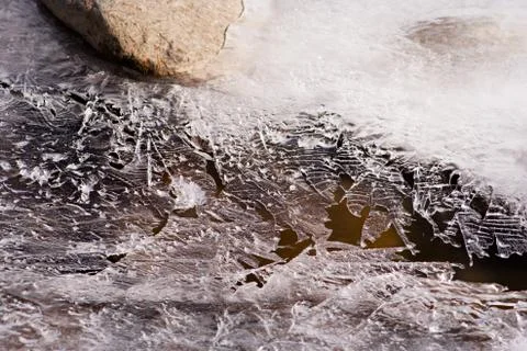 A thin plate of ice covering a small mountain stream in Austria. Stock Photos