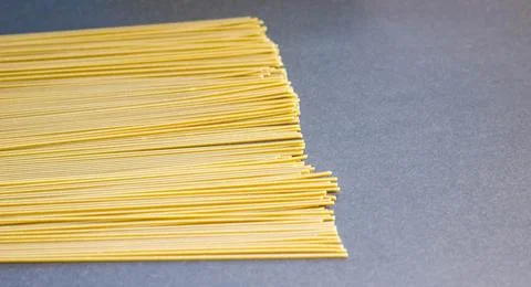 Thin raw spaghetti is scattered on a dark background. Foto stock