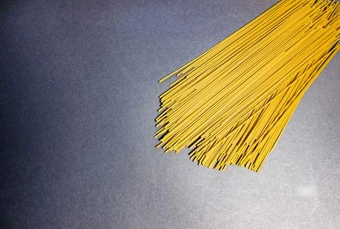 Thin raw spaghetti is scattered on a dark background. Foto stock