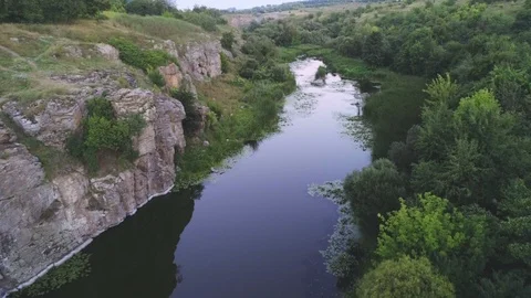 Thin river stretching between two rocky hills with wetland in summer Stock Footage 99728863