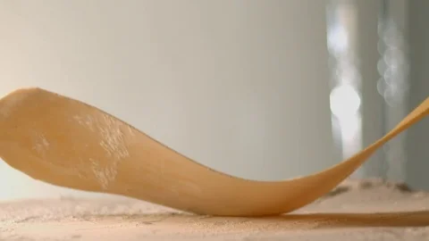 The thin rolled dough falls on the table with flour. Stock Footage 83723980