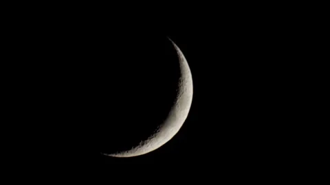 Thin silver crescent moon moving across dark sky Stock Footage 329656955