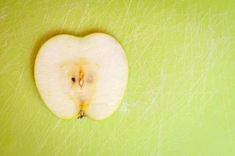 A thin slice of green apple on a cutting board. Stock Illustration
