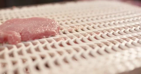 Thin slice of raw meat lying on a white plastic grid conveyor belt in a meat Vídeo Stock 339995057