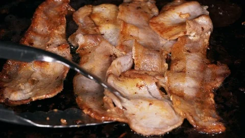 Thin sliced bacon frying on the iron pan in slow motion Video stock 95316615