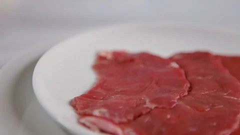 Thin sliced beef for delicious kebab on the rotating plate Stock Footage 130400138