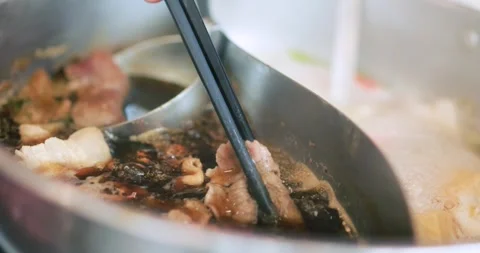 Thin sliced raw beef held with chopsticks over a hot pot, shabu, Asian cuis.. Stock Footage 346686799