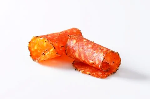 Thin slices of black pepper-coated salami speckled with pieces of Comte chees Stock Photos