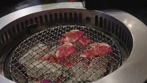 Thin slices of marbled beef topped with sesame seeds grilling over hot char.. Vídeos de archivo 334583648