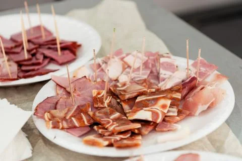 Thin slices of meat, ham, bacon lie on a white plate. Stock Photos