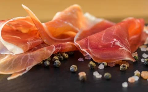 Thin slices of prosciutto with mixed with basil on wooden cutting board,vintage Stock Photos
