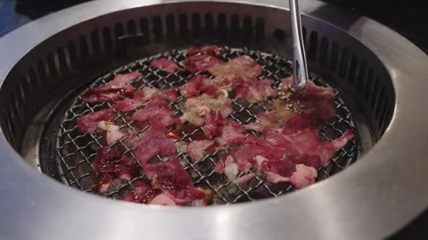 Thin slices of raw beef grilling on a traditional round wire mesh charcoal .. Stock-Footage 335939758