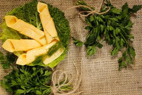 Thin slices of yellow cheese rolled into a straw on a green salad sheet on bu Stock Photos