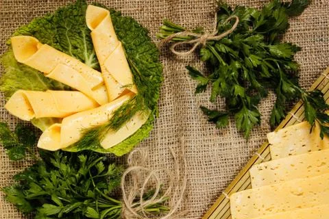 Thin slices of yellow cheese rolled into a straw on a green salad sheet on bu Stock Photos