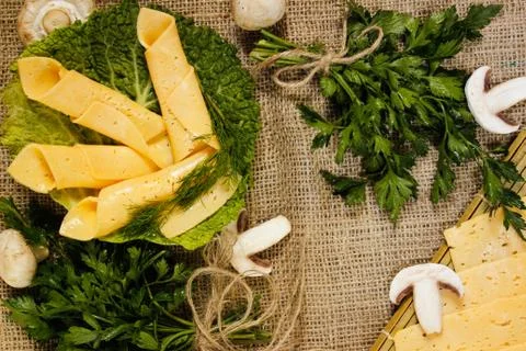 Thin slices of yellow cheese rolled into a straw on a green salad sheet and s Stock Photos