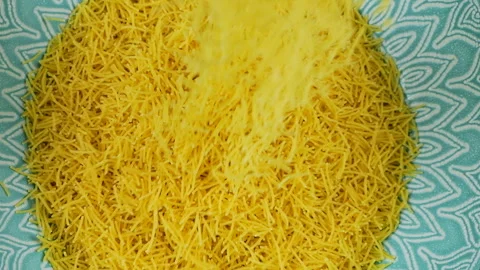 Thin small pasta is poured into a blue ceramic bowl. Top view. Slow motion.	 Stock Footage 304391519