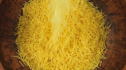 Thin small pasta is poured into a brown ceramic bowl. Top view. Slow motion. Stock Footage 304392165