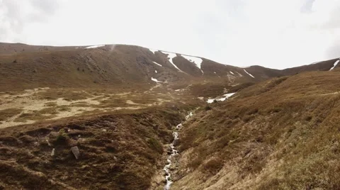 Thin Stream Covered With Withered Grass on Slopes of the Mountain Below Its Stock Footage 63962861