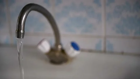 A thin stream of hard water flows from the tap from the old aerator. Old mixer. Stock Footage 183273435